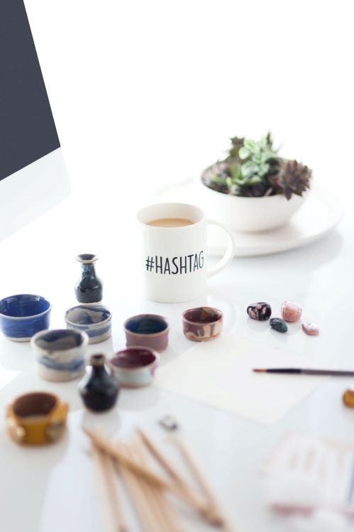 desktop with a hashtag mug succulent plant and stones on top