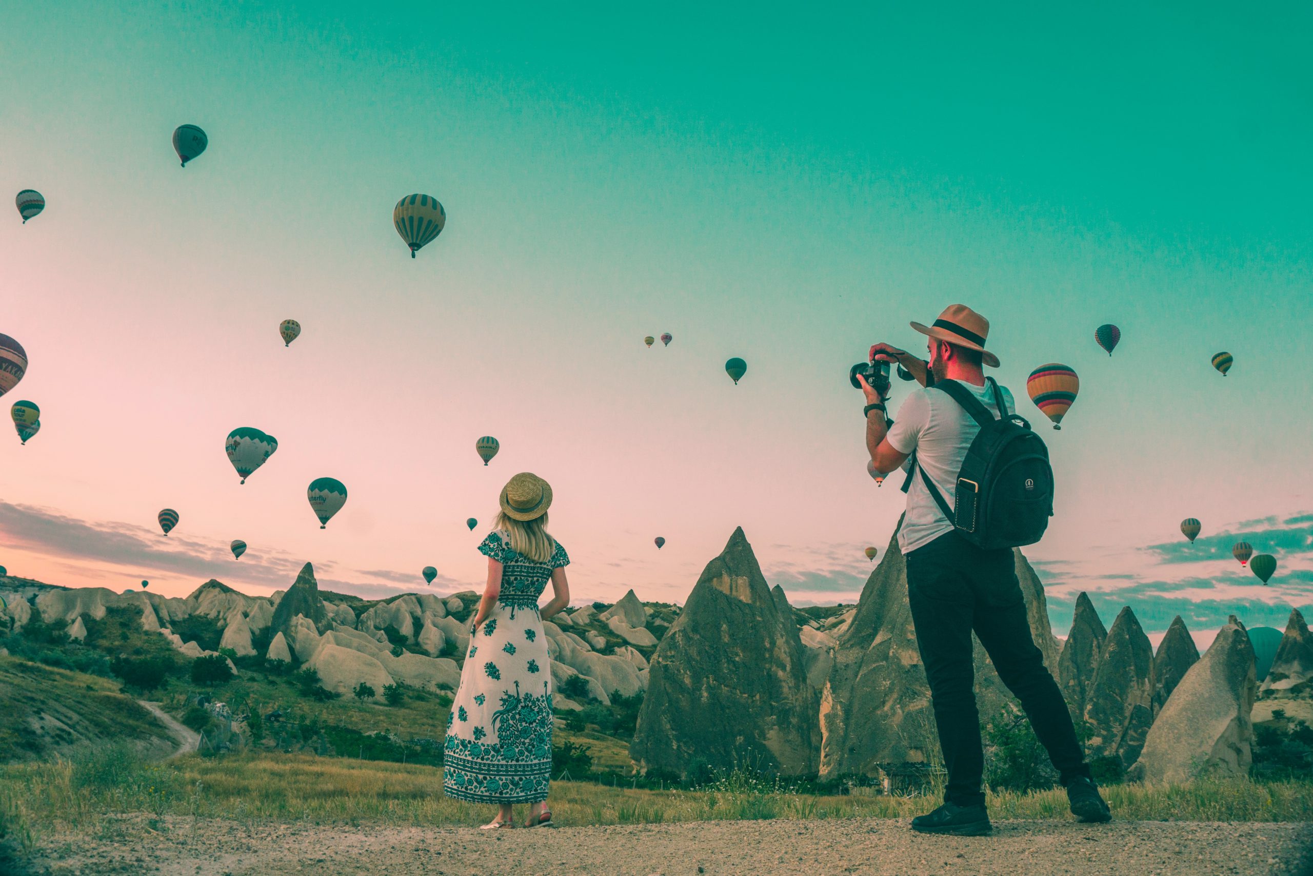 man photographing woman watching hot air balloons