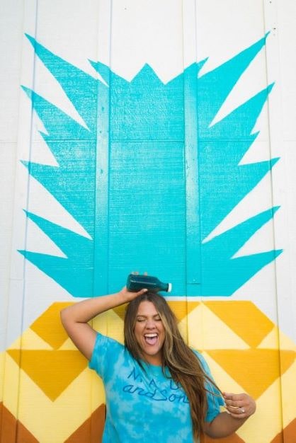 smiling woman posing in front of pineapple wall mural
