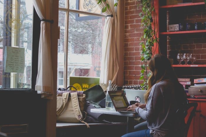 woman on computer facing window in cozy coffee shop