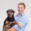 man in blue shirt holding black and brown dog