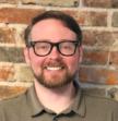 man wearing glasses smiling at the camera