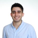 dark hair man with blue shirt smiling at camera