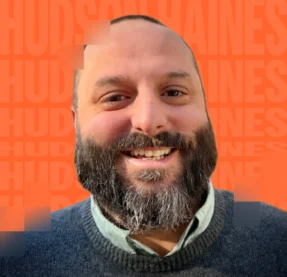 man smiling in front of orange background