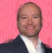 man smiling in front of pink background