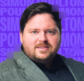 man smiling in front of purple background