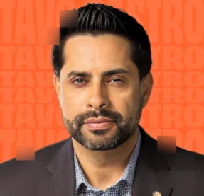 man smiling in front of orange background