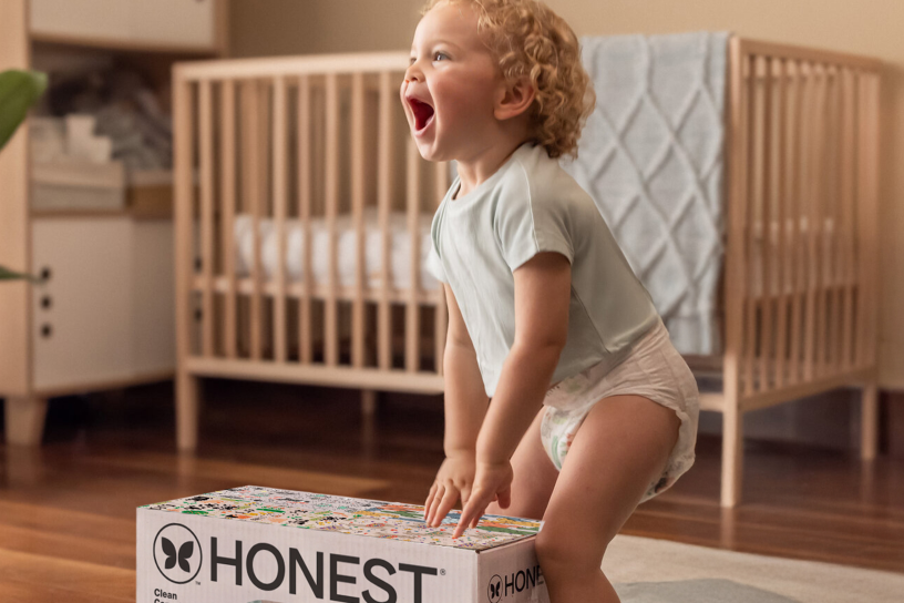 baby standing in front of diaper box